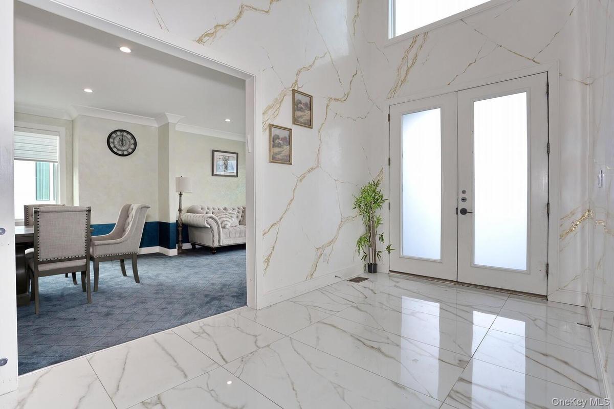 Entrance foyer with french doors, marble tiled floors, recessed lighting, and ornamental molding