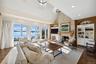 Living area with built in features, a stone fireplace, dark wood-type flooring, high vaulted ceiling, and recessed lighting