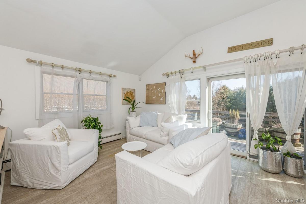 Living room featuring a baseboard heating unit, vaulted ceiling, and light wood-style flooring