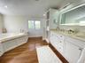 Bathroom with a wainscoted wall, a bath, double vanity, recessed lighting, and dark wood finished floors