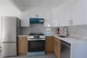 Kitchen featuring stainless steel appliances, tasteful backsplash, under cabinet range hood, and white cabinetry