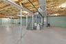 Expansive unfinished basement featuring a painted concrete floor, exposed joists with insulation, a utility staircase, and painted perimeter walls
