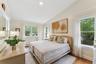 Bedroom with vaulted ceiling, light wood-style flooring, and baseboard heating