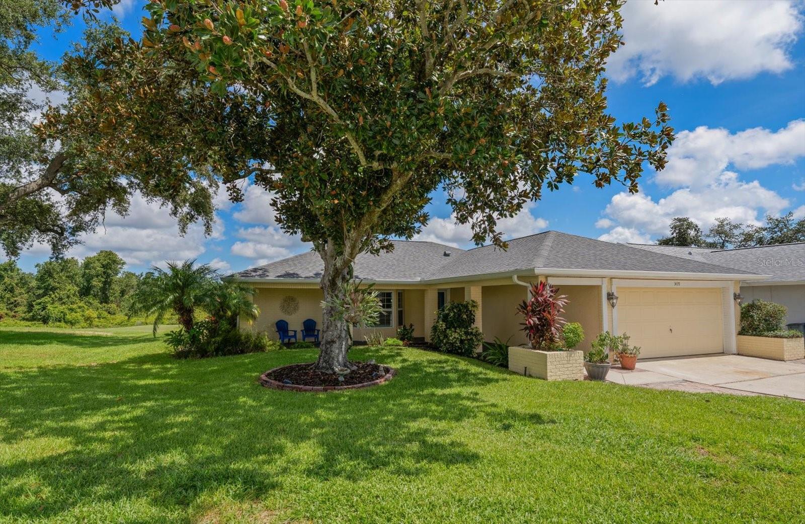 Front of home with shade tree and golf course beyond