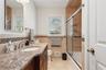 Full bathroom with vanity, tile walls, shower / bath combination with glass door, and toilet