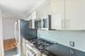 Kitchen with white cabinetry, stainless steel appliances, decorative backsplash, dark stone counters, and wood finished floors