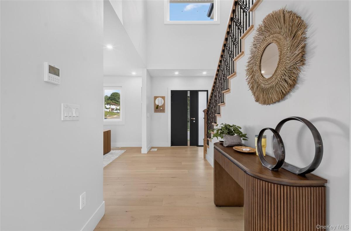 Double-height entryway with recessed lighting, wood-finish flooring, and a staircase featuring a wrought iron railing