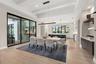 The adjacent dining room is refined, featuring a Schonbek Beyond Mystique LED linear pendant and glass sliding doors with access to the outdoor kitche