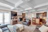 Carpeted living room featuring a wood stove, beamed ceiling, coffered ceiling, crown molding, and a textured ceiling