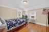 Bedroom with radiator heating unit, light wood finished floors, vaulted ceiling, and a textured ceiling