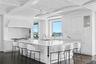 Kitchen with dark wood-style floors, white cabinetry, light countertops, a kitchen breakfast bar, and brick ceiling