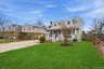 New england style home featuring a porch, a chimney, driveway, and roof with shingles