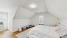 Bedroom featuring visible vents, baseboards, light wood finished floors, radiator, and lofted ceiling