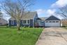 View of front facade with concrete driveway, a front yard, roof with shingles, and an attached garage