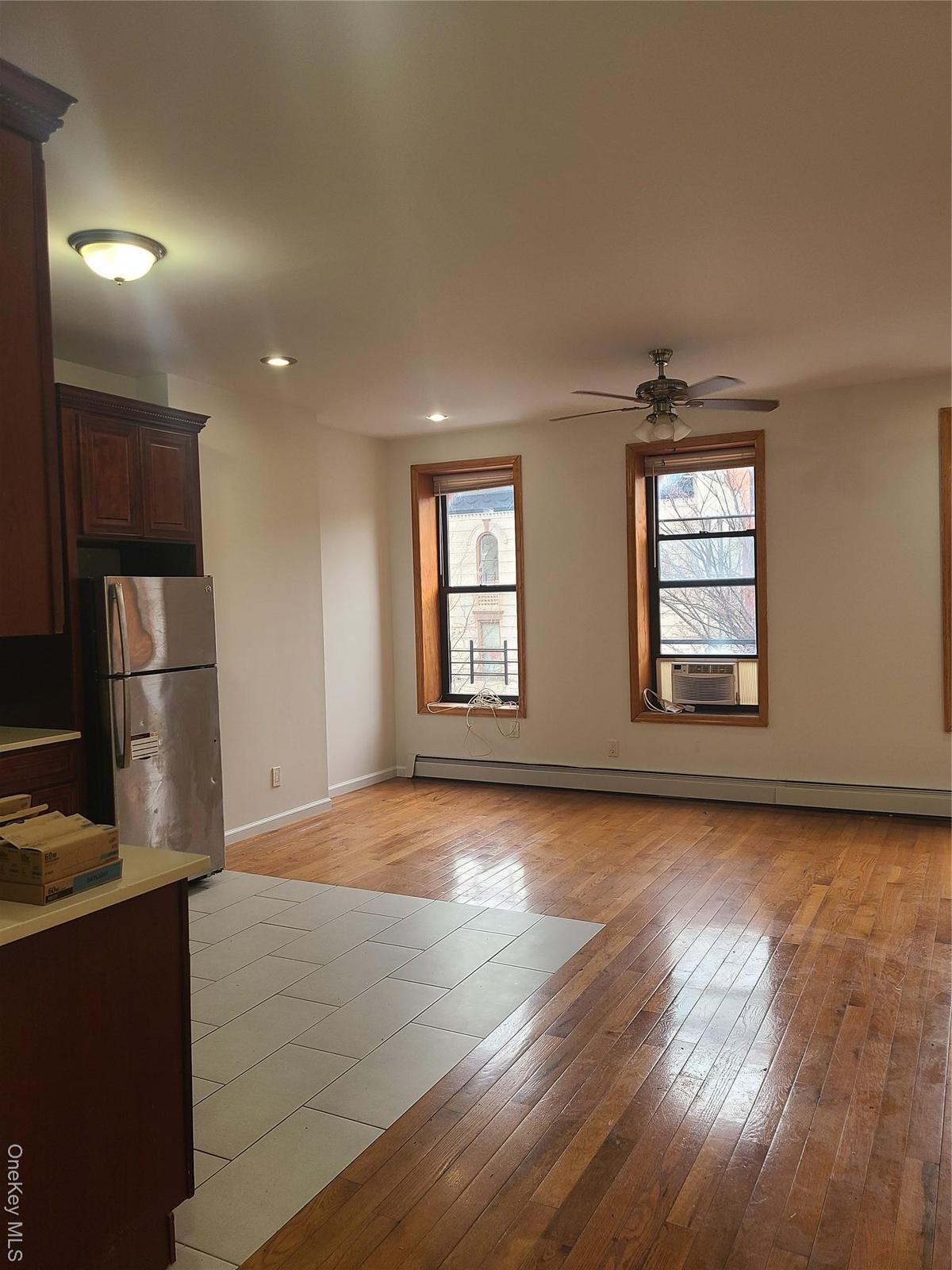 Unfurnished living room with baseboard heating, baseboards, light wood-style floors, ceiling fan, and recessed lighting