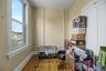 Sloped ceiling room featuring wood-finish flooring, a double window, and a flush-mount light fixture