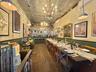 Dining room with an ornate ceiling, a chandelier, a wainscoted wall, wood-type flooring, and a community bar