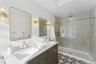 Full bathroom with double vanity, a sink, and a stall shower