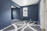 Interior room with dark blue wall paint, white trim, and a patterned area rug over a darker floor