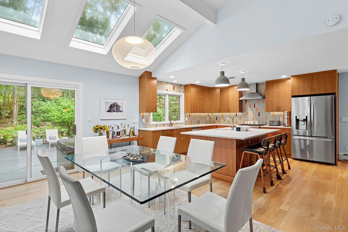 Dining space featuring light wood-style flooring, a skylight, beam ceiling, and high vaulted ceiling
