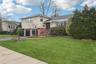 Tri-level home with brick siding, driveway, a front yard, and an attached garage
