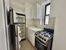 Kitchen with range with gas stovetop, freestanding refrigerator, white cabinets, light tile patterned flooring, and light countertops