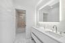 Bathroom with tiled shower / bath combo, vanity, and wooden walls