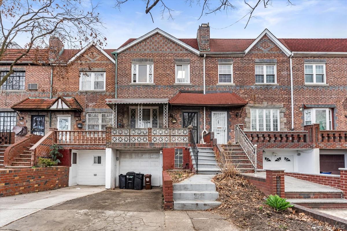 Townhome / multi-family property featuring a garage, concrete driveway, brick siding, and a chimney