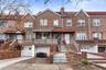 Townhome / multi-family property featuring a garage, concrete driveway, brick siding, and a chimney