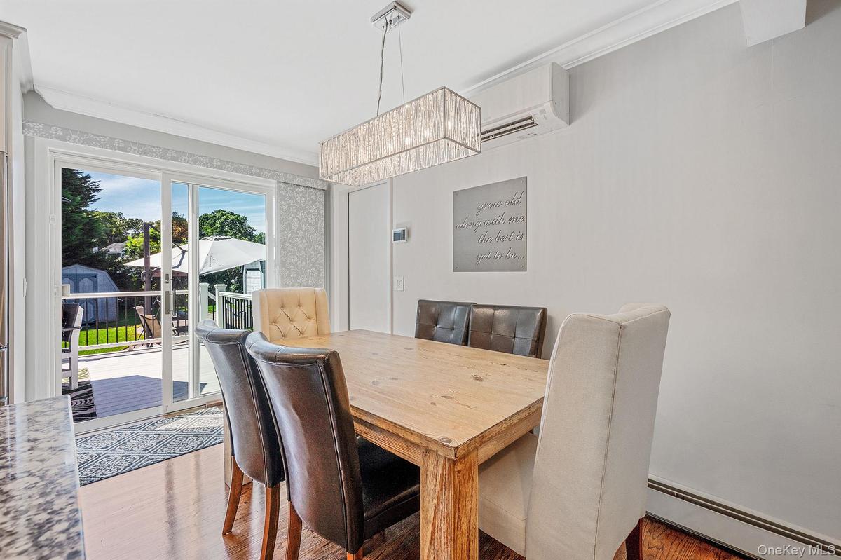 Dining room featuring a baseboard radiator, ornamental molding, wood finished floors, a wall unit AC, and a chandelier