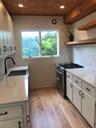Kitchen featuring open shelves, stove, light wood-style floors, a sink, and wooden ceiling