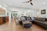 Open-concept living area featuring a brown leather sectional, wood-finish flooring throughout, and abundant recessed lighting