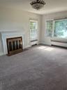 Unfurnished living room with radiator heating unit, carpet flooring, and a brick fireplace