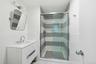 Bathroom with vanity, a shower with door, and tile walls