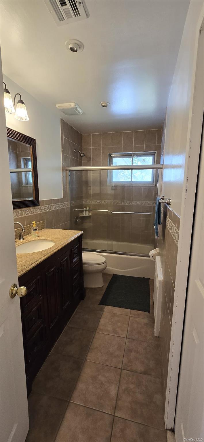 Bathroom featuring a dark wood-finish vanity with a stone countertop and undermount sink
