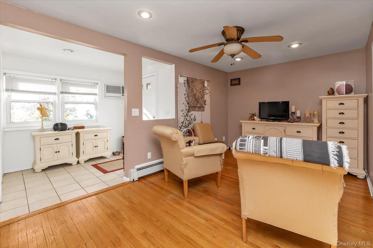 Office area with light wood-style flooring, a baseboard heating unit, ceiling fan, recessed lighting, and a wall mounted AC