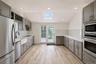 Kitchen featuring wood-finish flooring, gray cabinetry, built-in stainless steel appliances, a white farmhouse sink with a matte black faucet, and a s