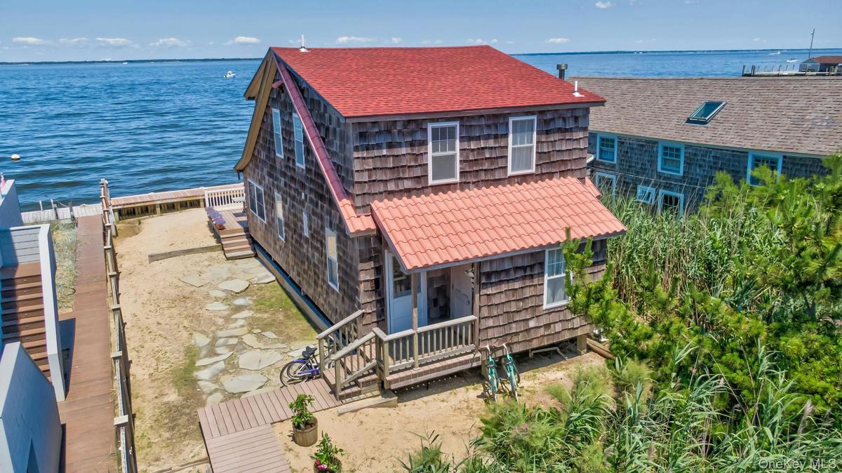 Waterfront residence featuring shingle siding and a red roof