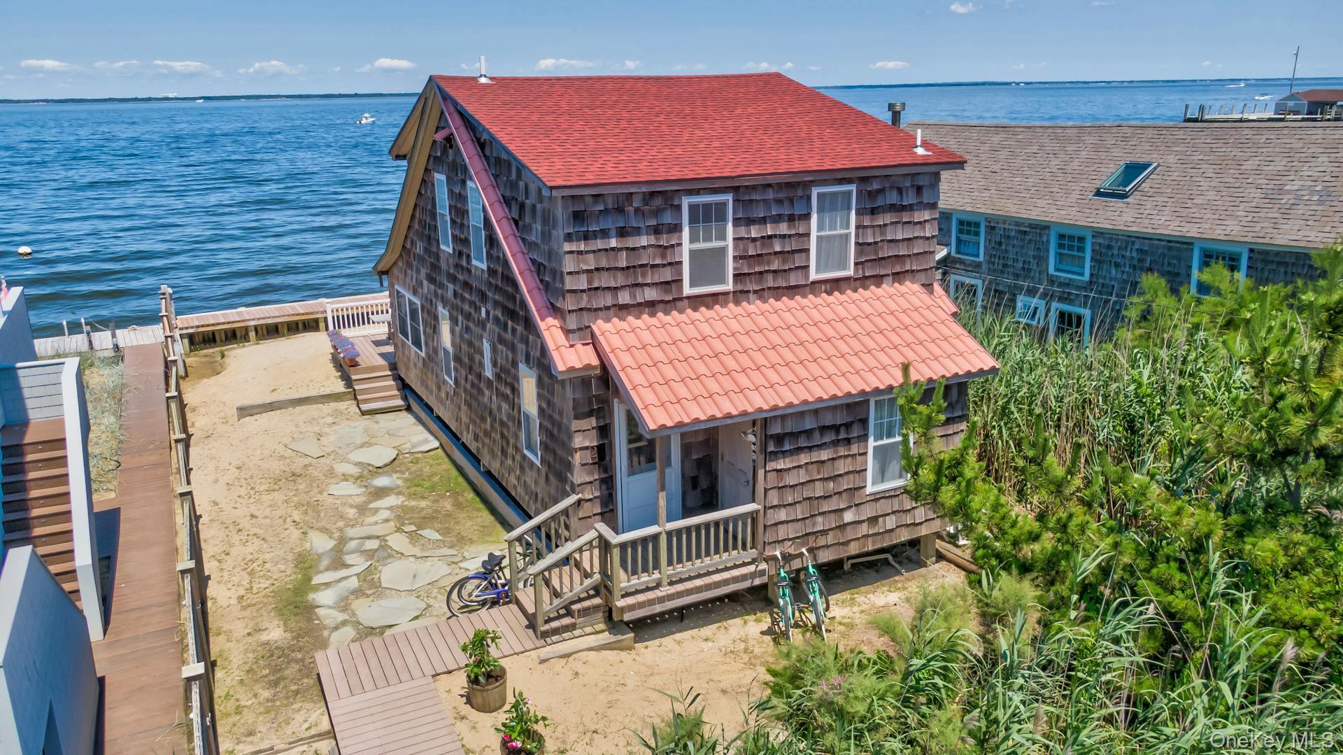 Waterfront residence featuring shingle siding and a red roof