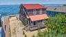 Waterfront residence featuring shingle siding and a red roof