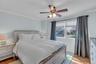 Bedroom with wainscoting, crown molding, light wood-style floors, and a ceiling fan