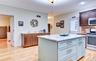 Legal accessory apartment: Kitchen featuring a central island with quartz countertop, light wood flooring, dark wood cabinetry, and stainless steel ap