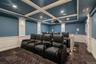 Cinema featuring a decorative wall, wainscoting, dark colored carpet, coffered ceiling, and beam ceiling