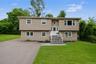 Split-level residence featuring tan vinyl siding and white trim windows