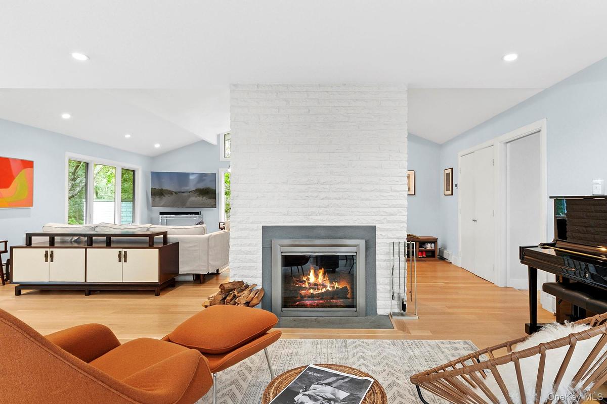 Living area featuring lofted ceiling, recessed lighting, light wood finished floors, and a brick fireplace