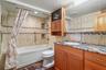 Bathtub- shower combo and a tastefully built in TV enhances the fully tiled guest bathroom.