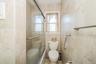 Bathroom featuring floor-to-ceiling ceramic tile, a glass-enclosed shower-tub combination, and a window with frosted privacy glass