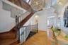 Impressive upper-level hallway featuring soaring ceilings, rich hardwood flooring, a beautifully crafted open staircase with decorative iron balusters