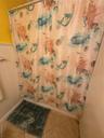 Bathroom featuring shower / tub combo with curtain and a wainscoted wall