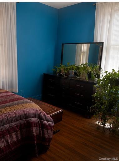 Room featuring wood-finish flooring and a corner window with horizontal blinds and sheer drapes